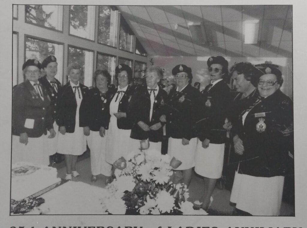 Une photo en noir et blanc de dix femmes habillés de vestons et de jupes, avec des chapeaux militaires. Sous la photo est inscrit « 25th anniversary of Ladies Auxiliary »