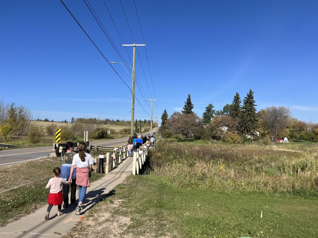 Des enfants marchent sur un pont en bois en bordure de route.